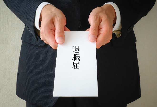退職届を差し出すスーツ姿の男性。