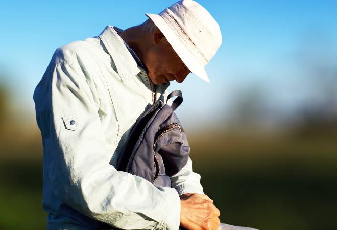 ベンチに座りうつむく高齢男性。